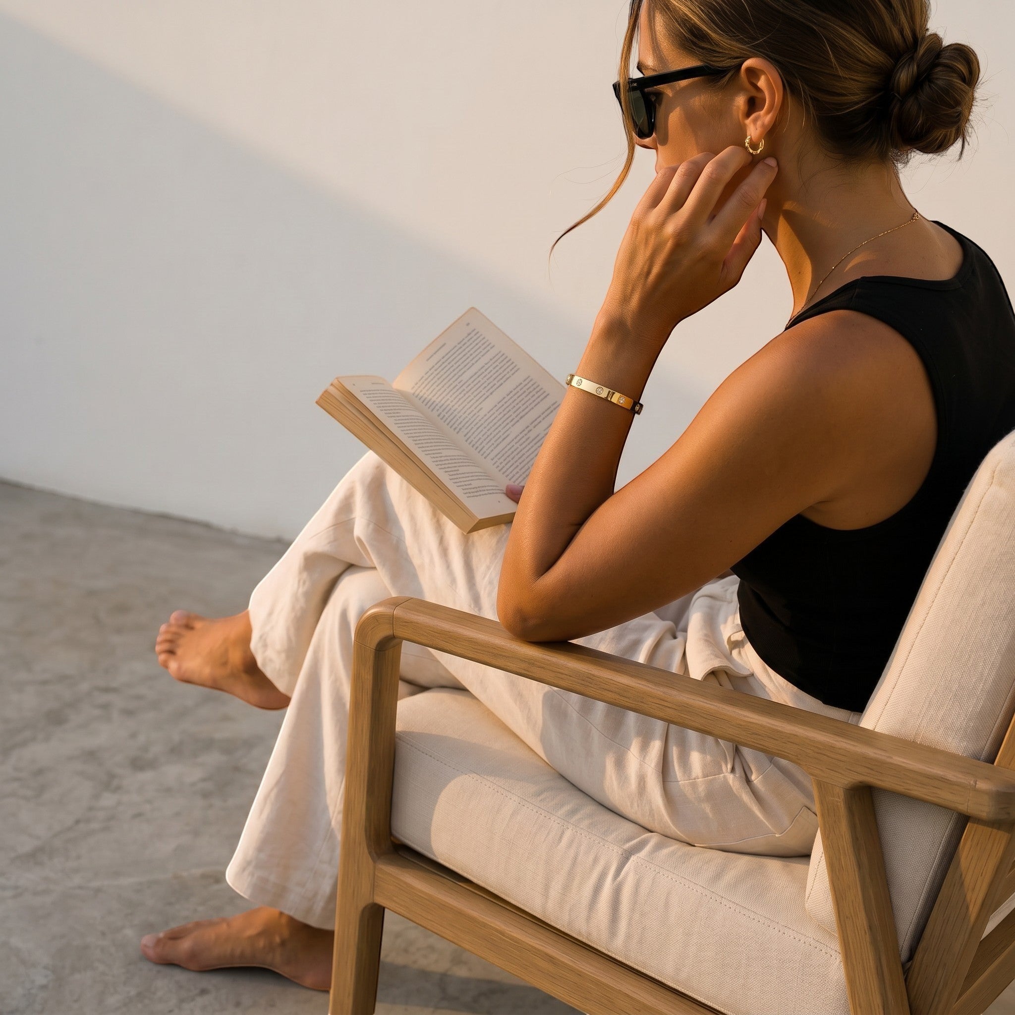Mein Shop gold clover bangle with zirkonia stones on a woman reading a book.