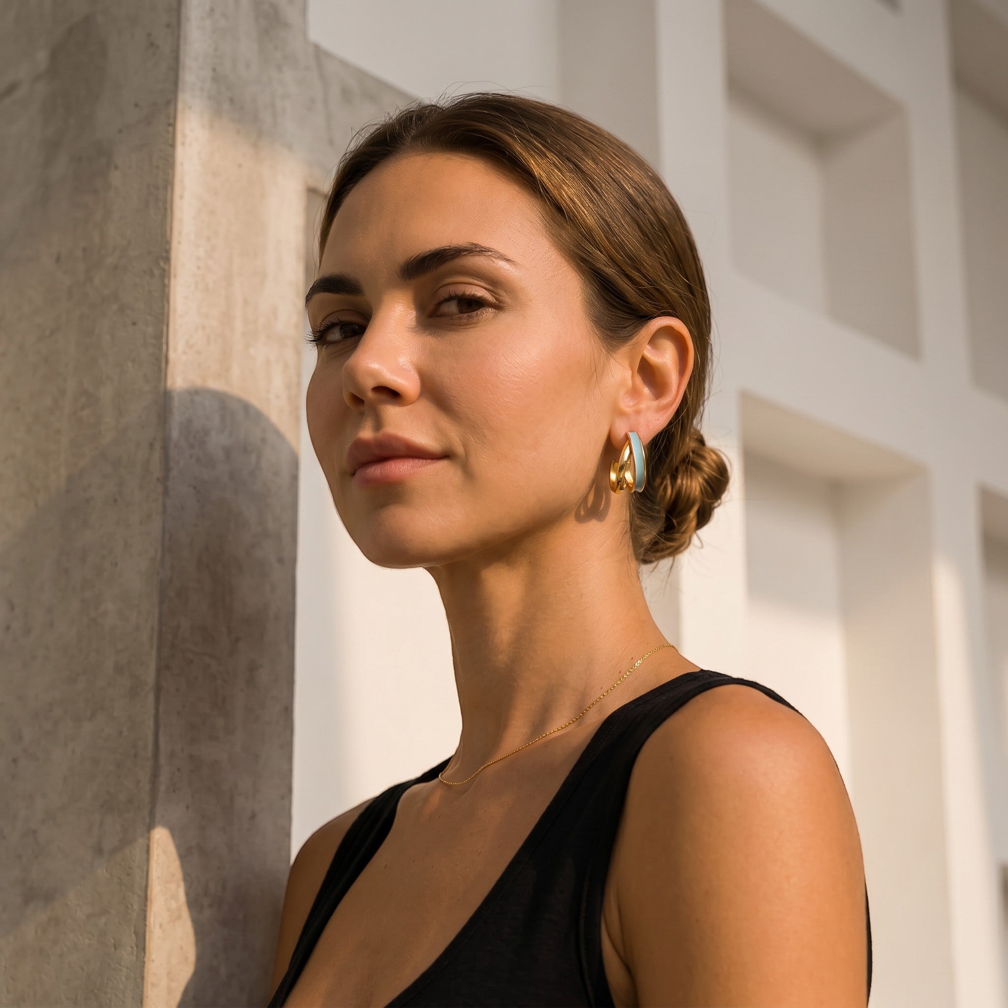 Mein Shop gold and light blue enamel hoop earrings worn by a woman with her hair in a bun.