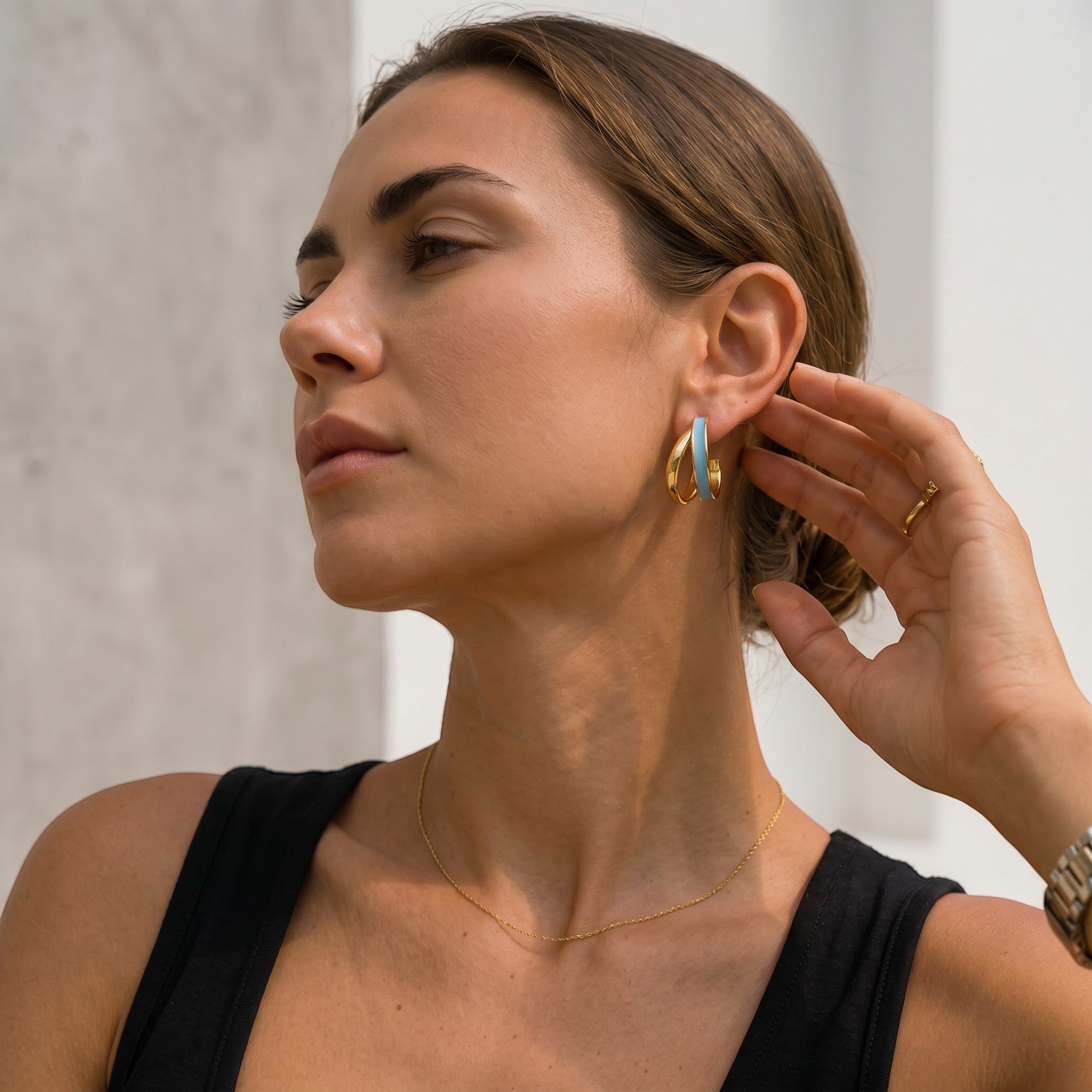 Mein Shop gold hoop earrings with light blue enamel detail, worn by a woman.